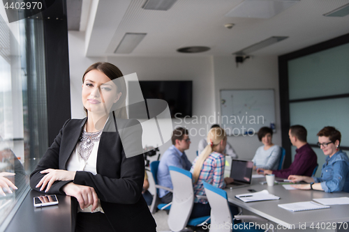 Image of Elegant Woman Using Mobile Phone by window in office building