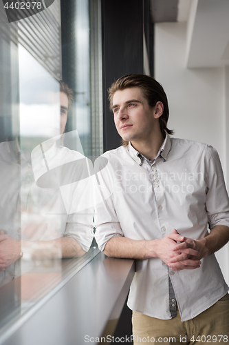Image of young businessman in startup office by the window