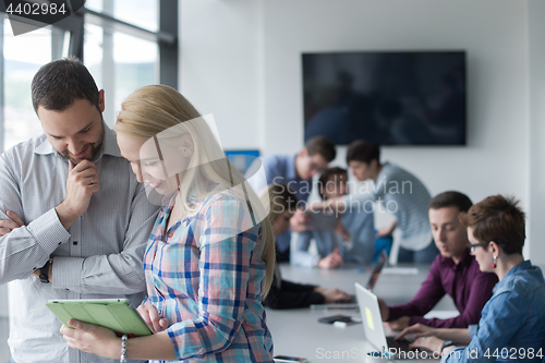 Image of Two Business People Working With Tablet in office