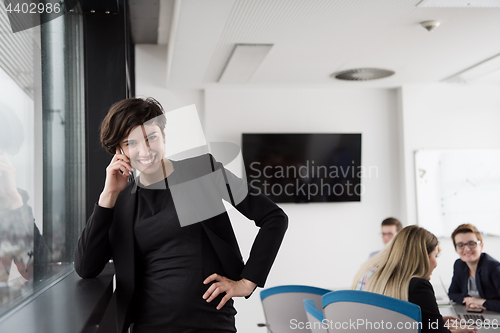 Image of Elegant Woman Using Mobile Phone by window in office building