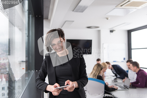 Image of Elegant Woman Using Mobile Phone by window in office building