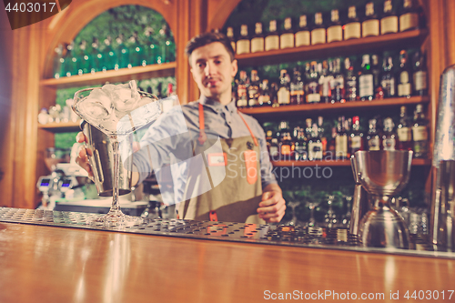 Image of Expert barman is making cocktail at night club.