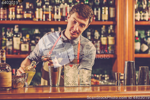 Image of Expert barman is making cocktail at night club.