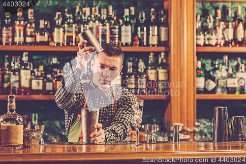 Image of Barman making an alcoholic cocktail at the bar counter on the bar background