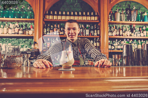 Image of Barman offering an alcoholic cocktail at the bar counter on the bar background