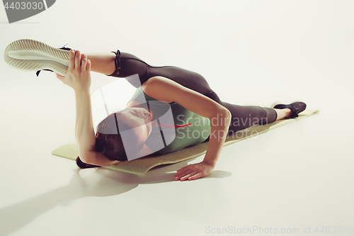 Image of Beautiful slim brunette doing some stretching exercises in a gym