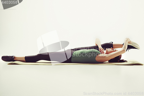 Image of Beautiful slim brunette doing some stretching exercises in a gym