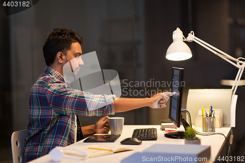 Image of creative man with computer working at night office