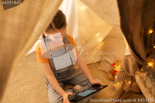 Image of little girl with tablet pc in kids tent at home