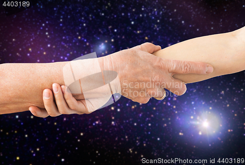 Image of close up of senior and young woman holding hands