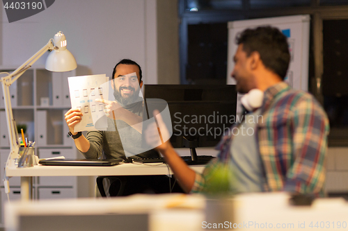 Image of creative man showing papers to colleague at office