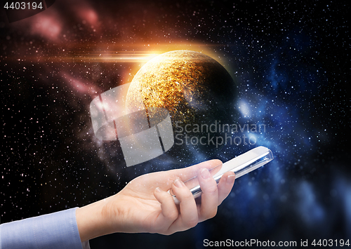 Image of hand holding smartphone over planet in space