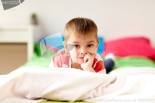 Image of portrait of little boy lying on bed at home
