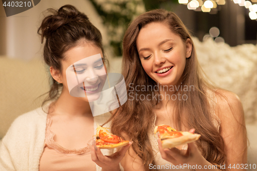 Image of happy female friends eating pizza at home