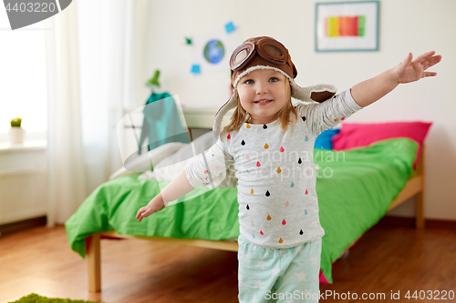 Image of happy little girl in pilot hat playing at home