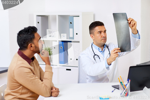 Image of doctor with x-ray and male patient at clinic