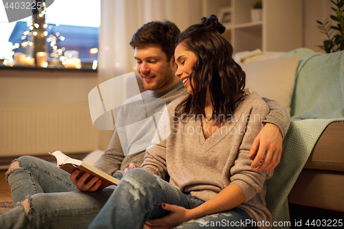 Image of happy couple reading book at home