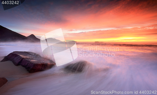 Image of Ocean sunrise as large waves wash onto the beach