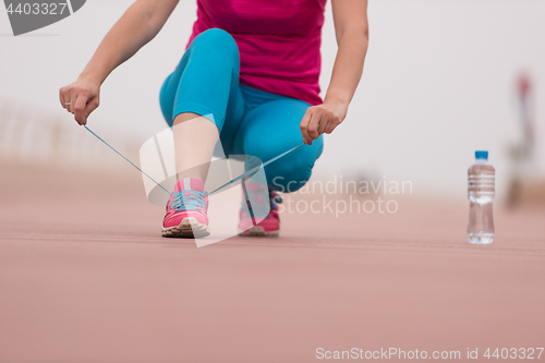 Image of Young woman tying shoelaces on sneakers