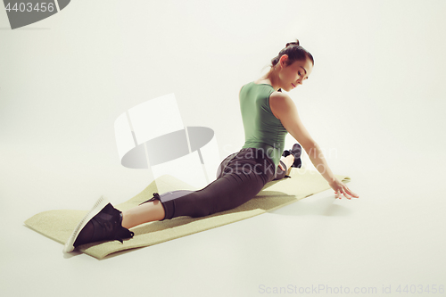 Image of Beautiful slim brunette doing some stretching exercises in a gym