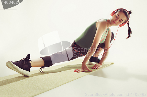 Image of Front view of a young woman stretching body in gymnastics class.