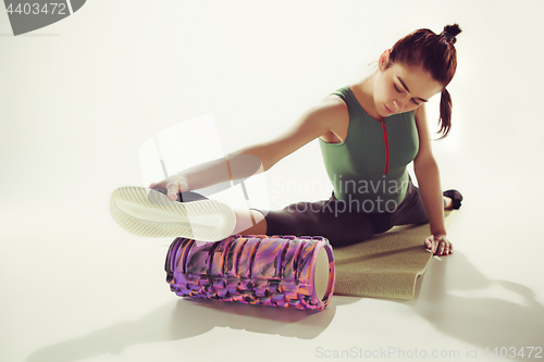 Image of Beautiful slim brunette doing some stretching exercises in a gym