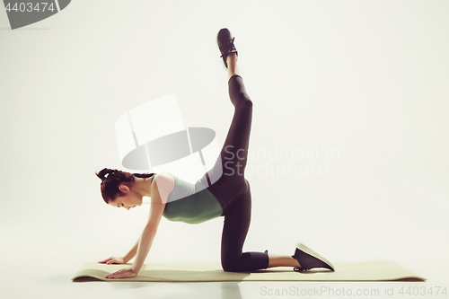 Image of Beautiful slim brunette doing some stretching exercises in a gym