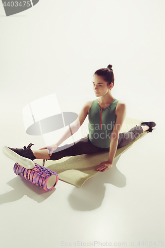 Image of Beautiful slim brunette doing some stretching exercises in a gym