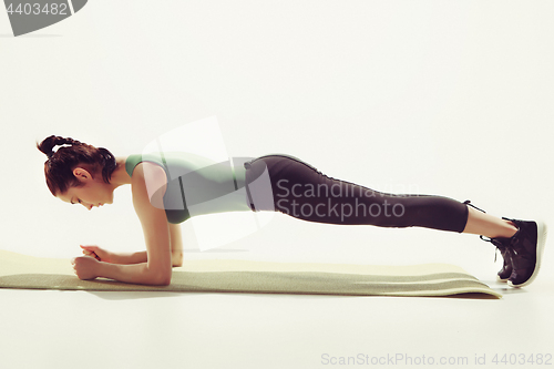 Image of Beautiful slim brunette doing some stretching exercises in a gym