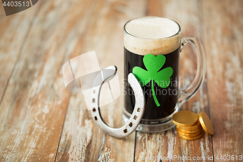 Image of shamrock on glass of beer, horseshoe and coins