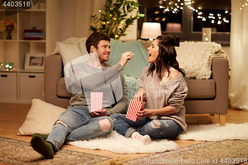 Image of happy couple eating popcorn at home