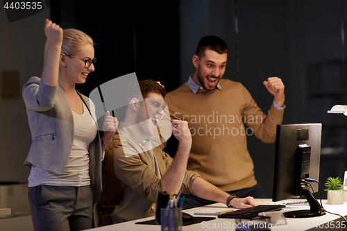Image of business team celebrating success at night office