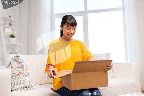 Image of happy asian young woman with parcel box at home