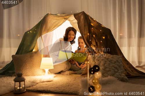 Image of happy family reading book in kids tent at home