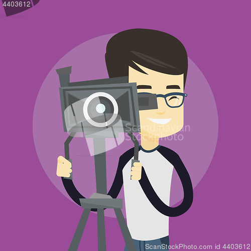 Image of Cameraman with movie camera on tripod.