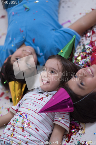 Image of kids  blowing confetti while lying on the floor