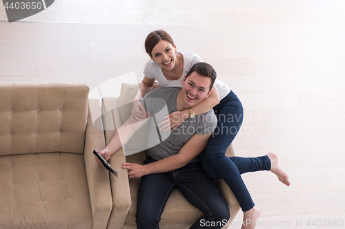 Image of couple relaxing at  home with tablet computers