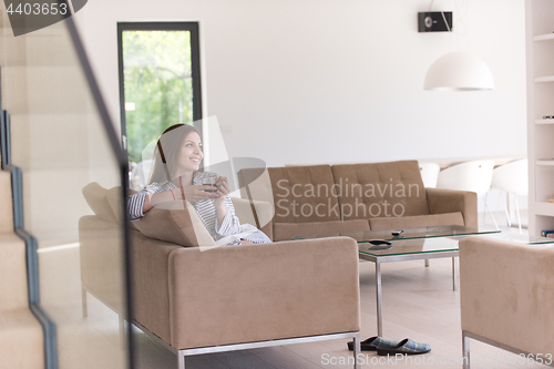 Image of young woman in a bathrobe enjoying morning coffee