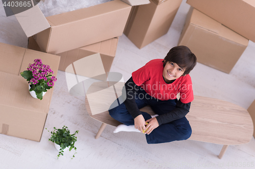 Image of boy sitting on the table with cardboard boxes around him top vie