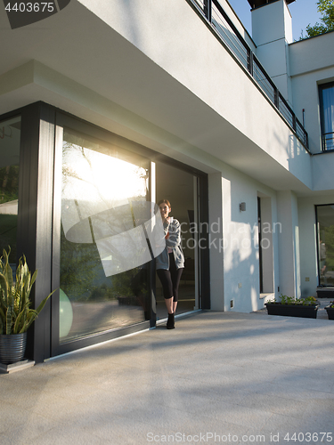 Image of woman drinking coffee in front of her luxury home villa