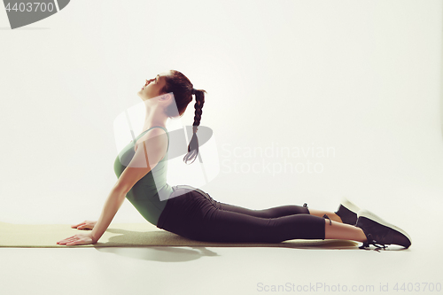 Image of Beautiful slim brunette doing some stretching exercises in a gym