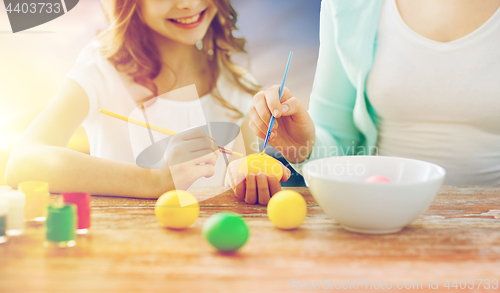 Image of daughter and mother coloring easter eggs