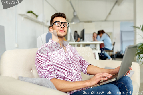 Image of man in eyeglasses with laptop working at office