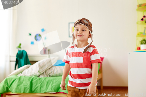 Image of happy little boy in pilot hat playing at home