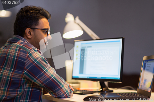 Image of creative man working with laptop at night office