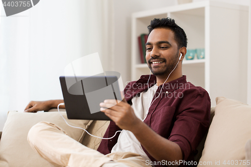 Image of man in earphones with tablet pc listening to music