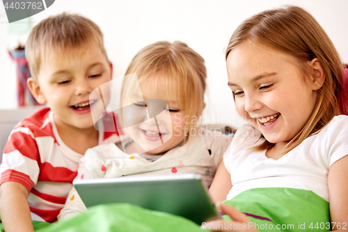 Image of happy little kids with tablet pc in bed at home