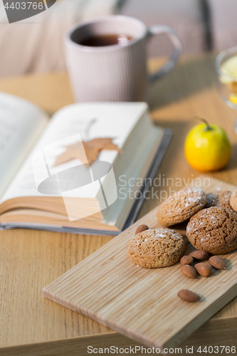 Image of oat cookies, almonds and book on table at home