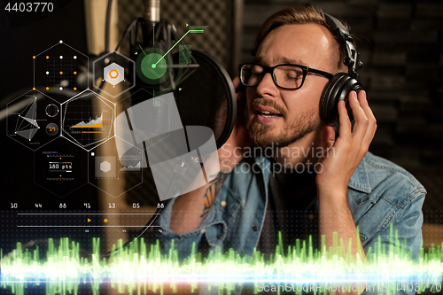 Image of man with headphones singing at recording studio