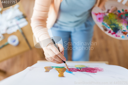 Image of artist with palette and brush painting at studio